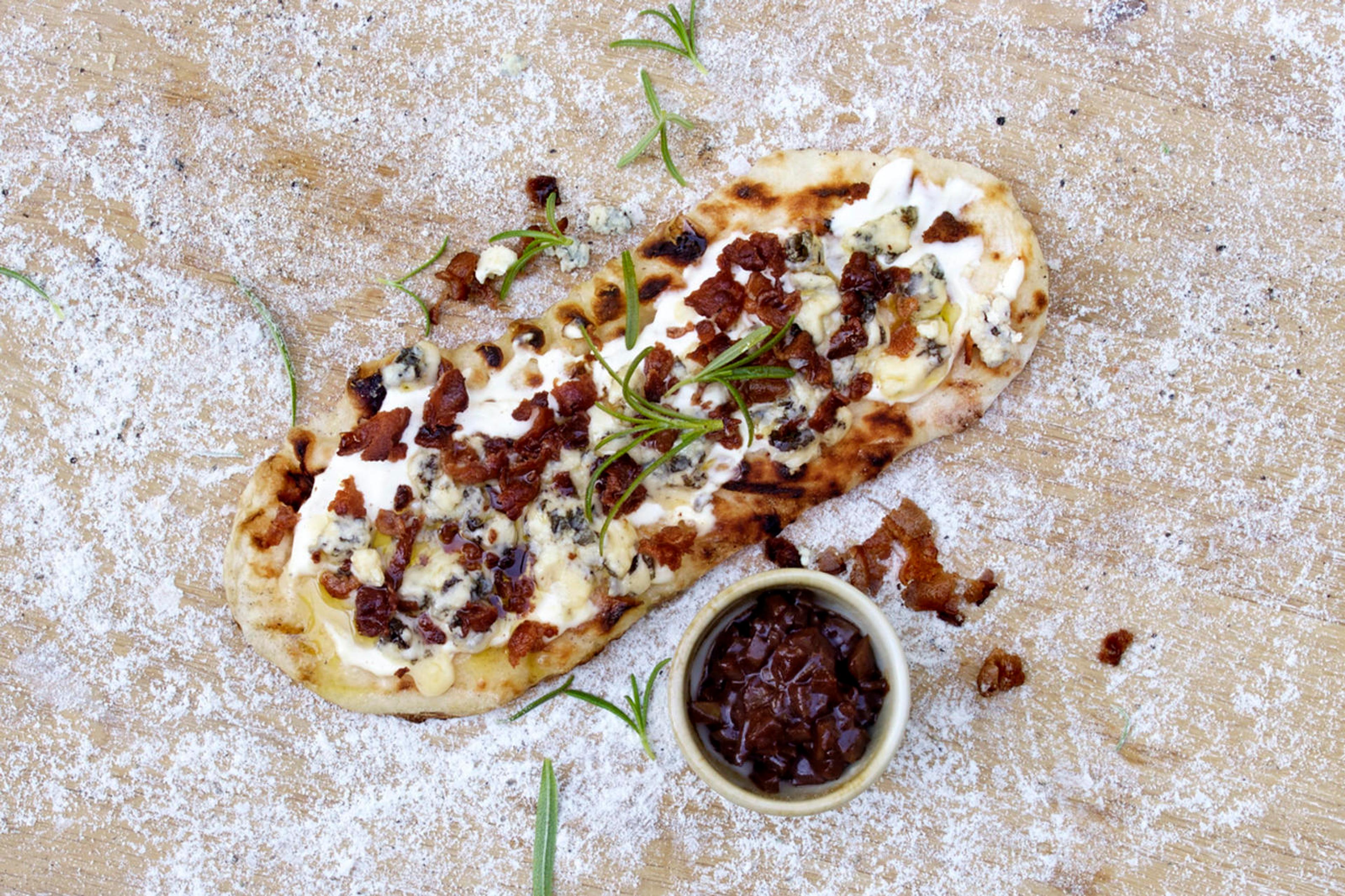 Hjemmelaget pizza med hvit pizzasaus, toppet med blåmuggost og bacon.