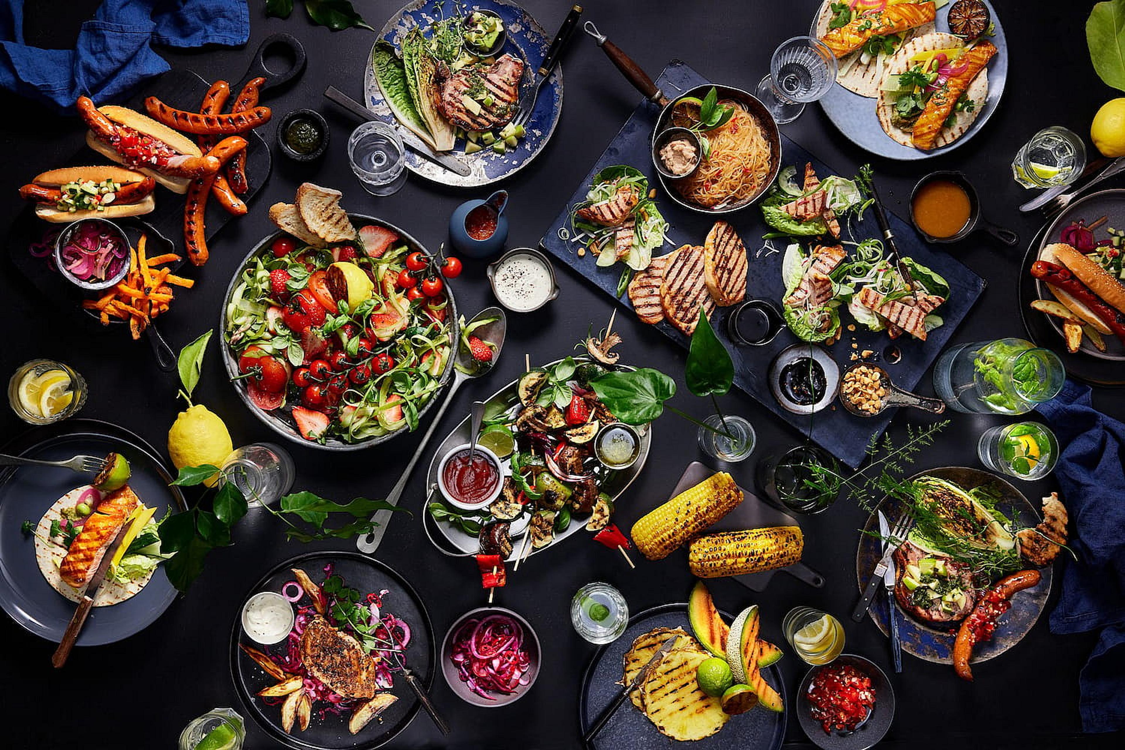 Bilde av et bord fylt med ulike retter og grønnsaker fra grillenn