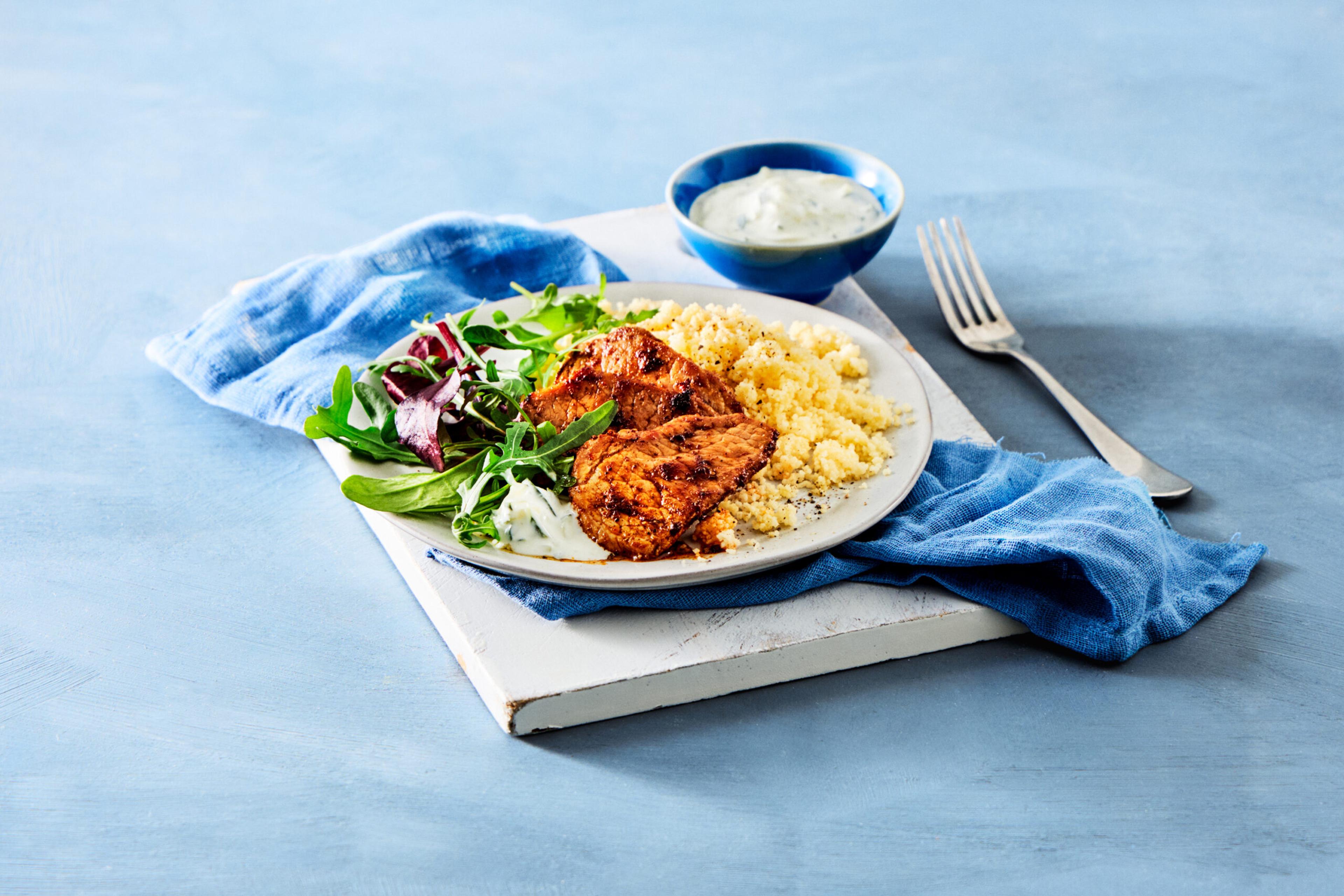 Svinefilet servert med couscous, rucolasalat og tzatziki.