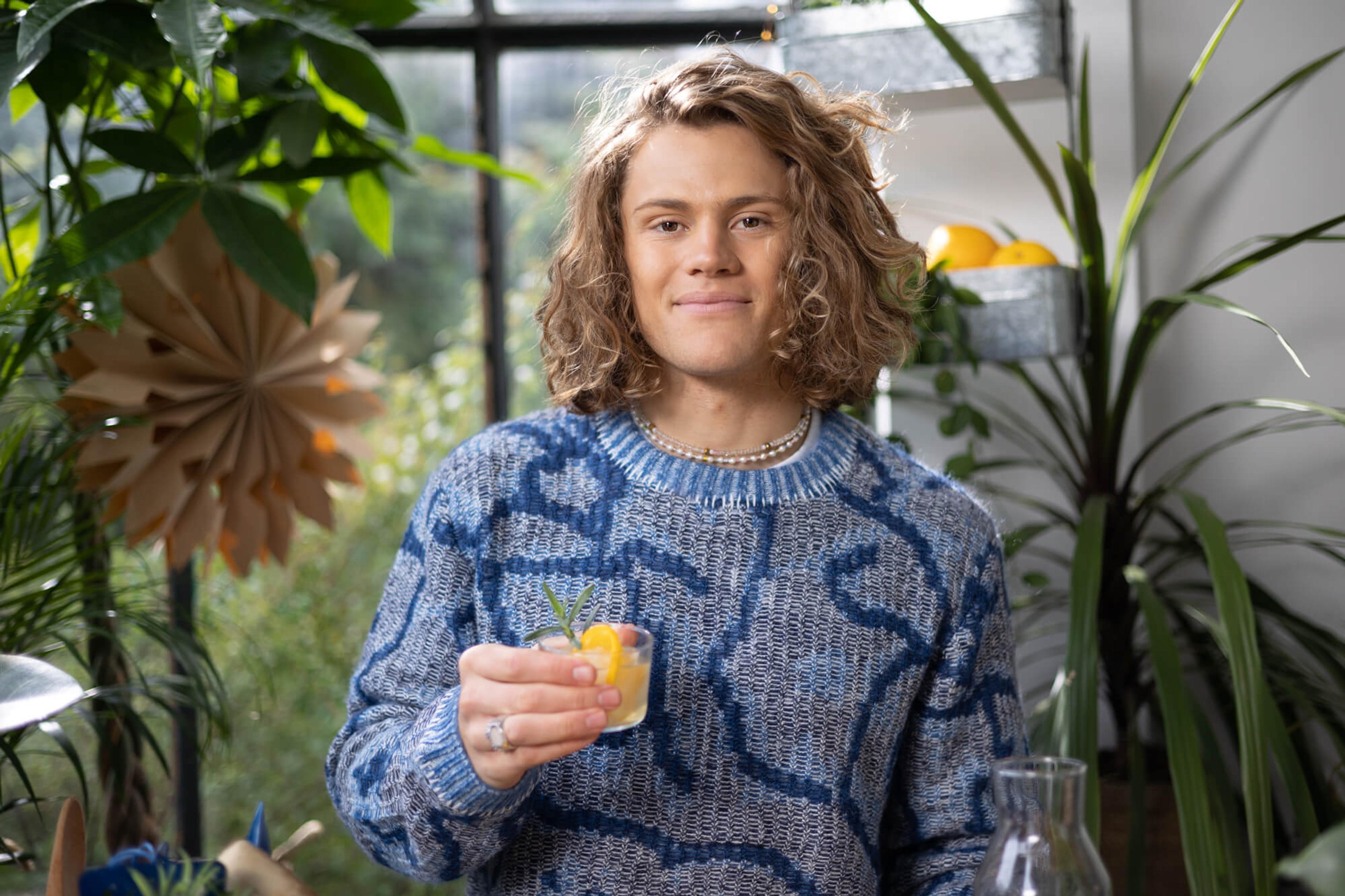 lucas står med glas smed limonade og isbiter med skiver av appelsin