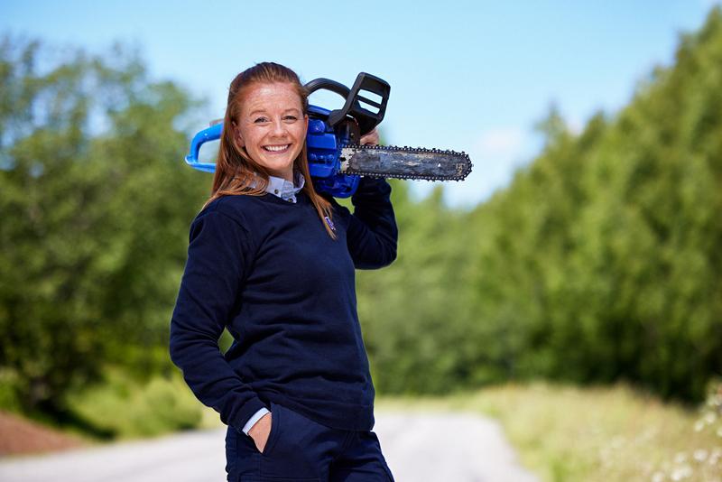 Ansatt med motorsag på skulderen utendørs.