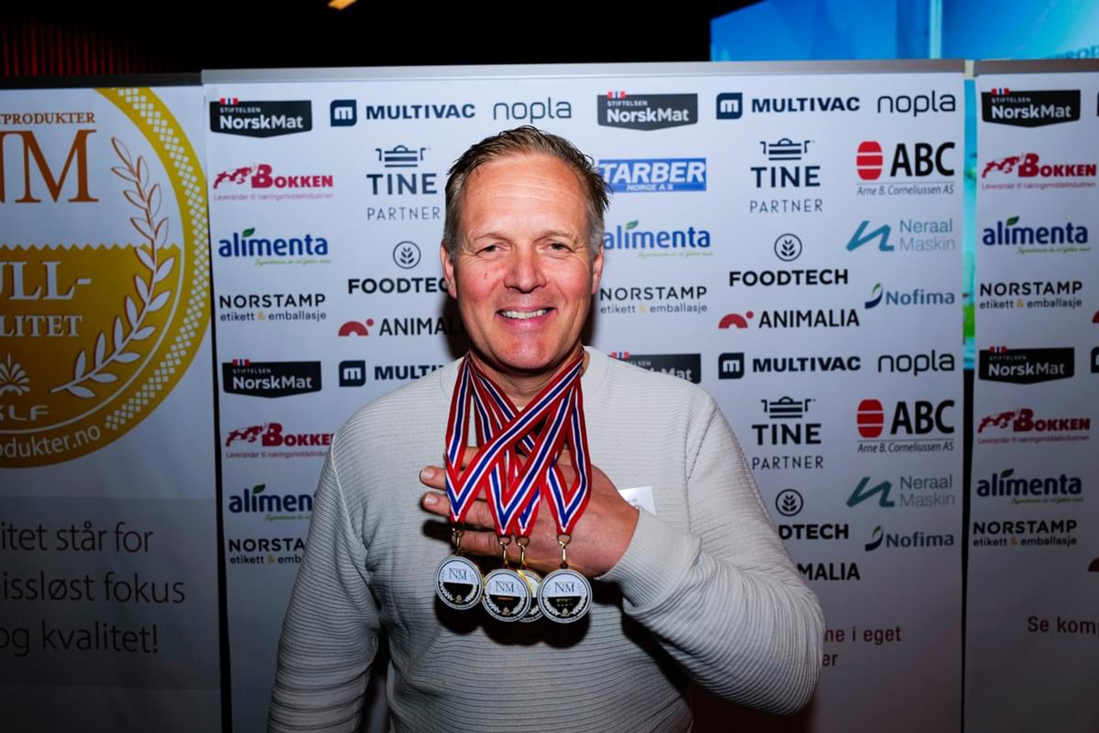 Stig Muri fra Nordfjord med fire medaljer foran presseveggen i NM i grillprodukter.