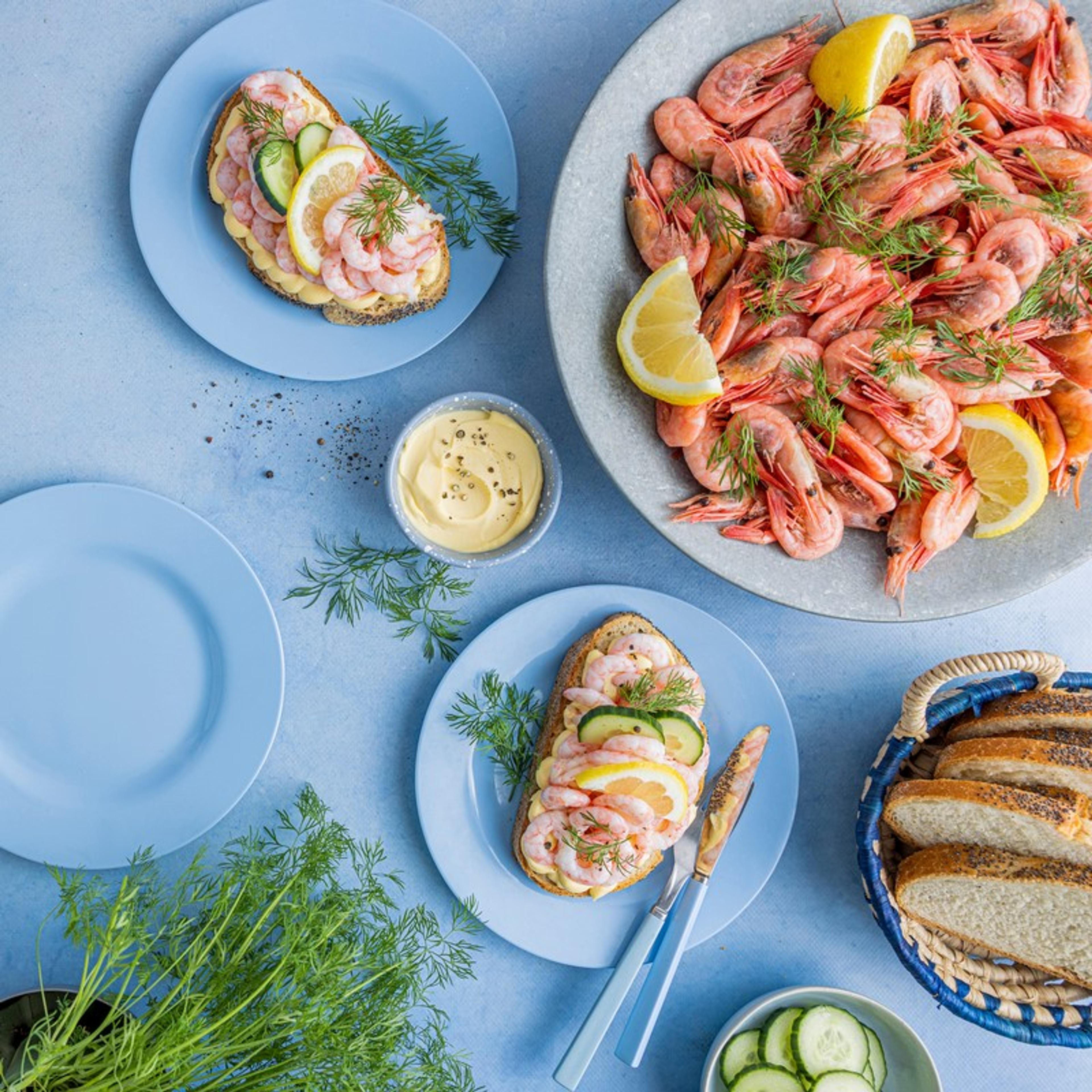 Tapasbord med spekemat, ost, reker, røkelaks, oliven, frukt, bær og brød servert på ulike fat.