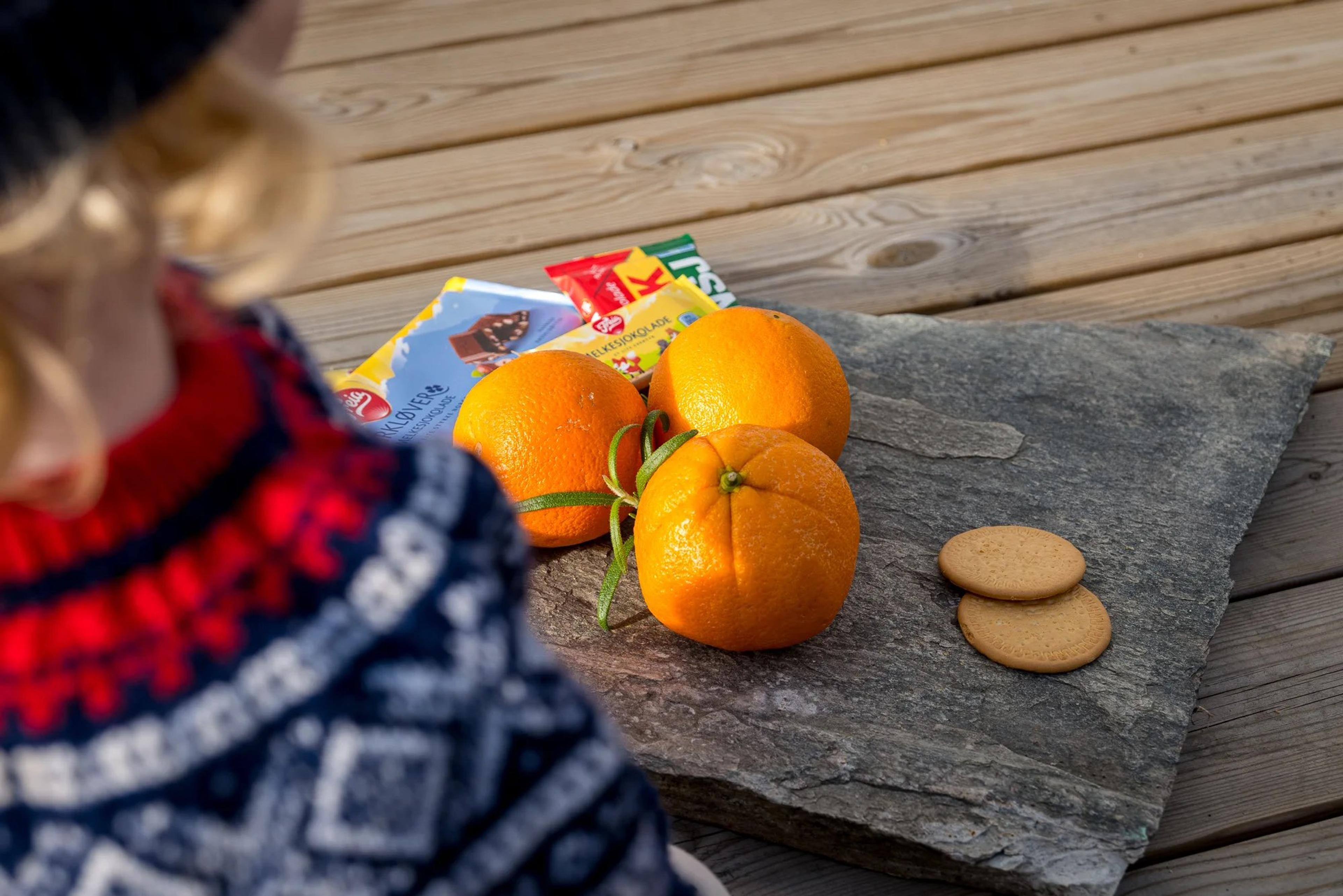 appelsin på en stenplate med sjokolade og mariekjeks liggende rundt