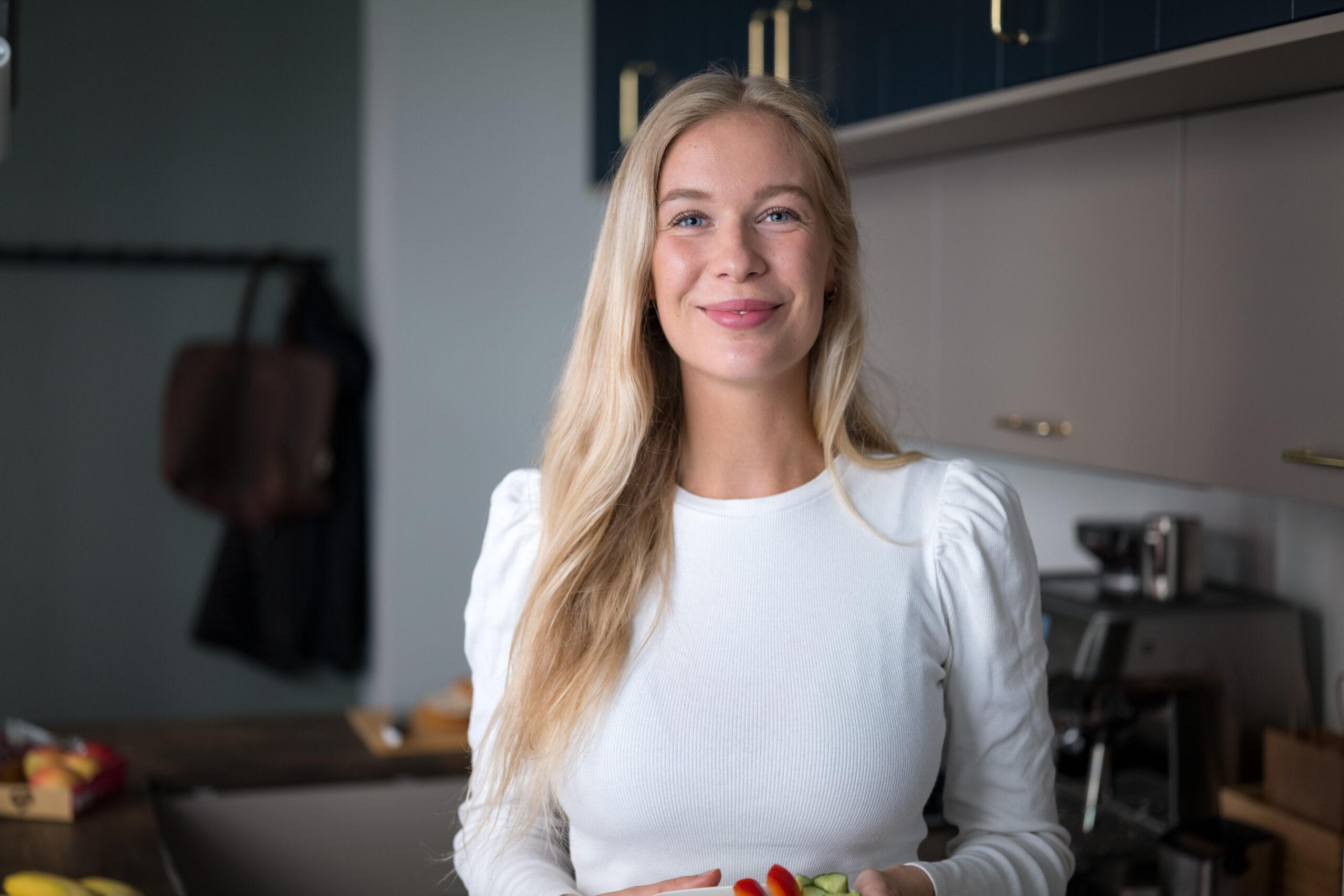 karen fra fattig student smiler inn i kamera med restemat i hånden