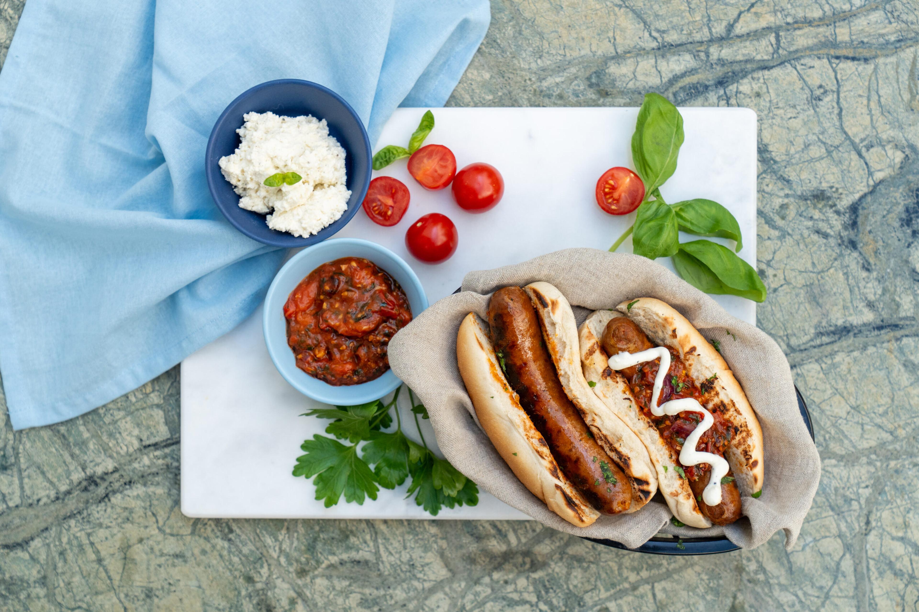 To grillet ndujapølser i brød med sprøstekt løk, grillede tomater og en frisk fetaostkrem