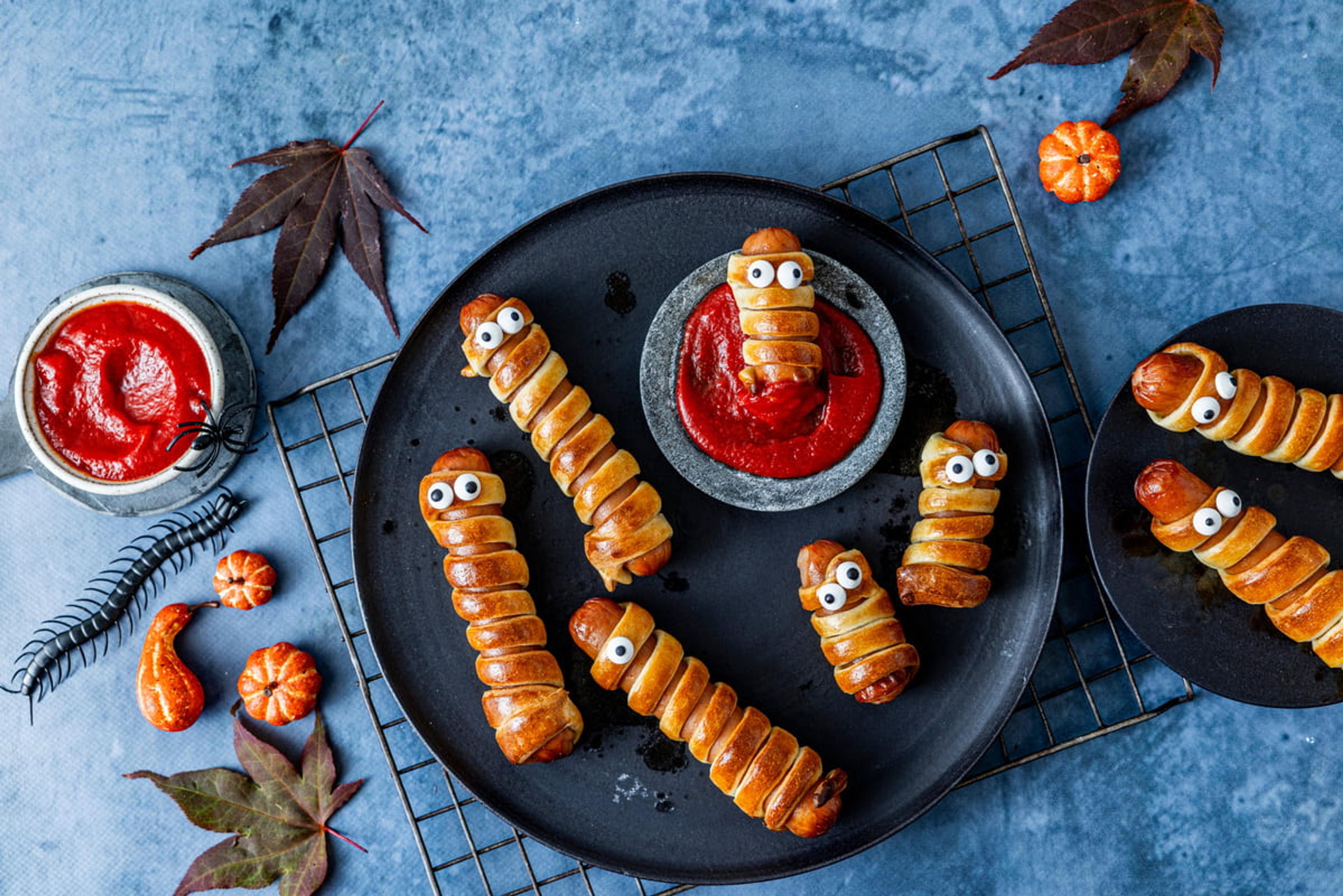 Pølser surret i deig og dekorert som mumier, servert med ketchup til Halloween.