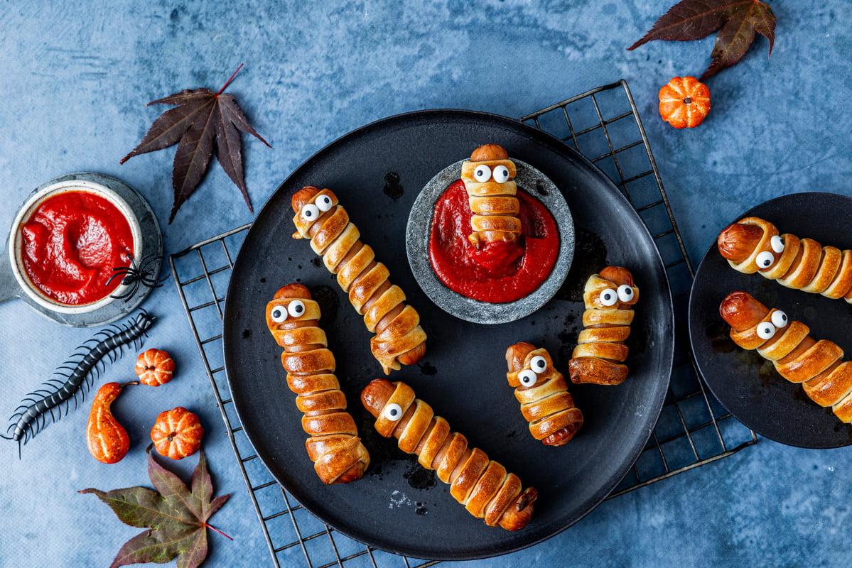 Pølser surret i deig og dekorert som mumier, servert med ketchup til Halloween.