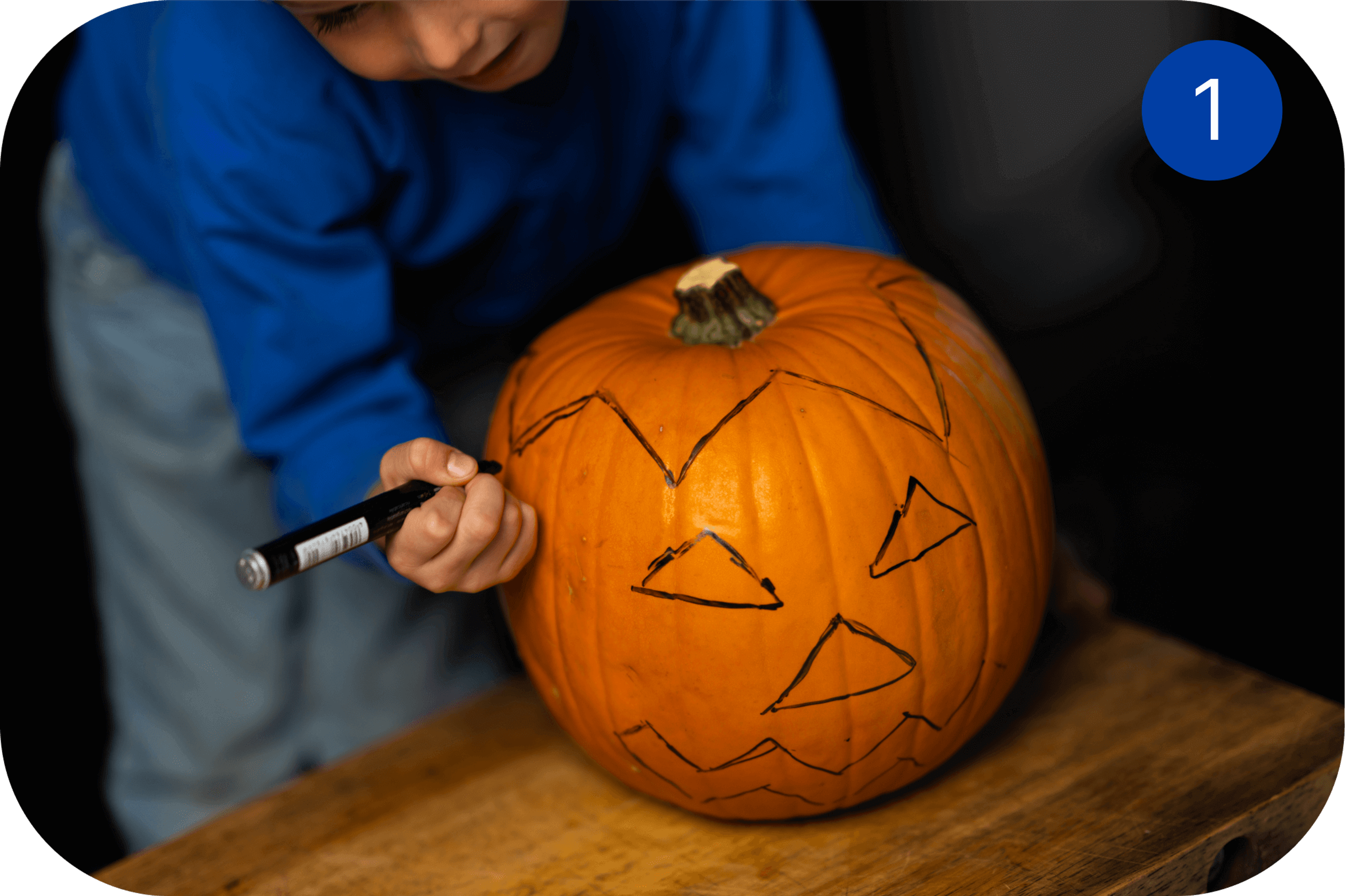  Person tegner ansikt på et gresskar før utskjæring til Halloween.