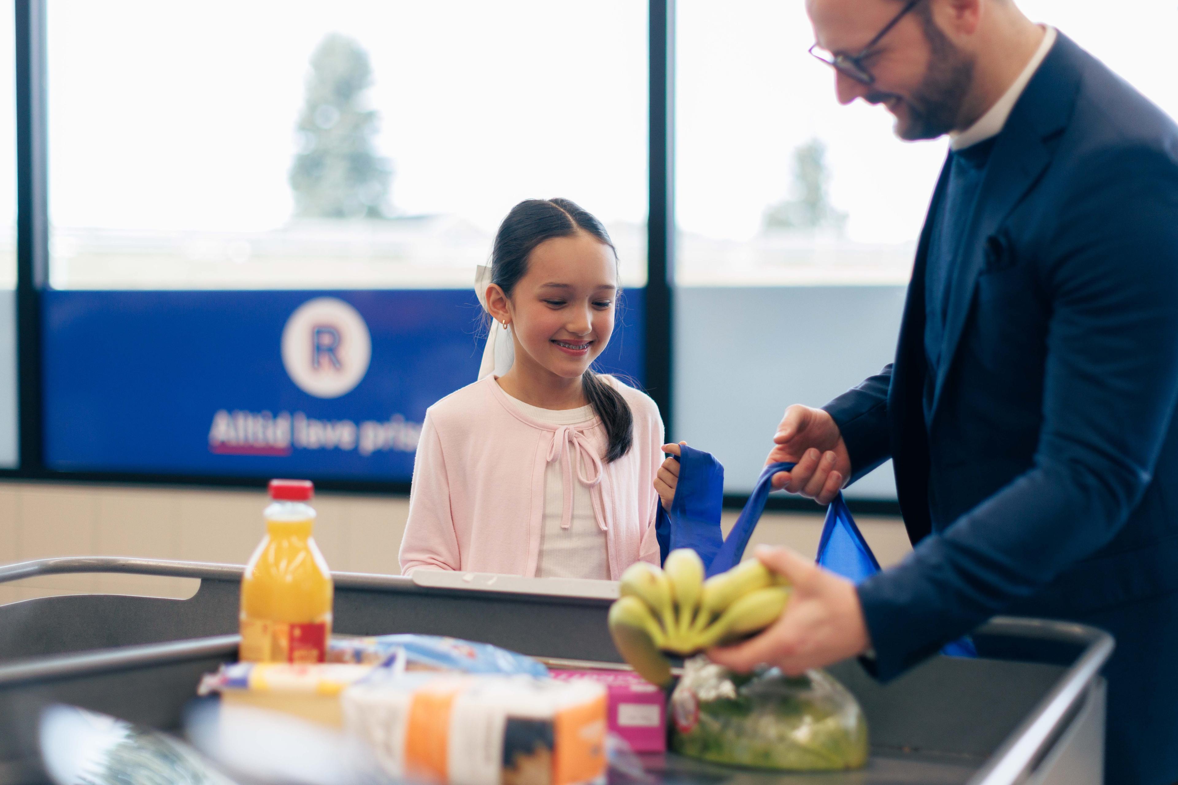Jente som hjelper å pakke varer i handlenett på butikken