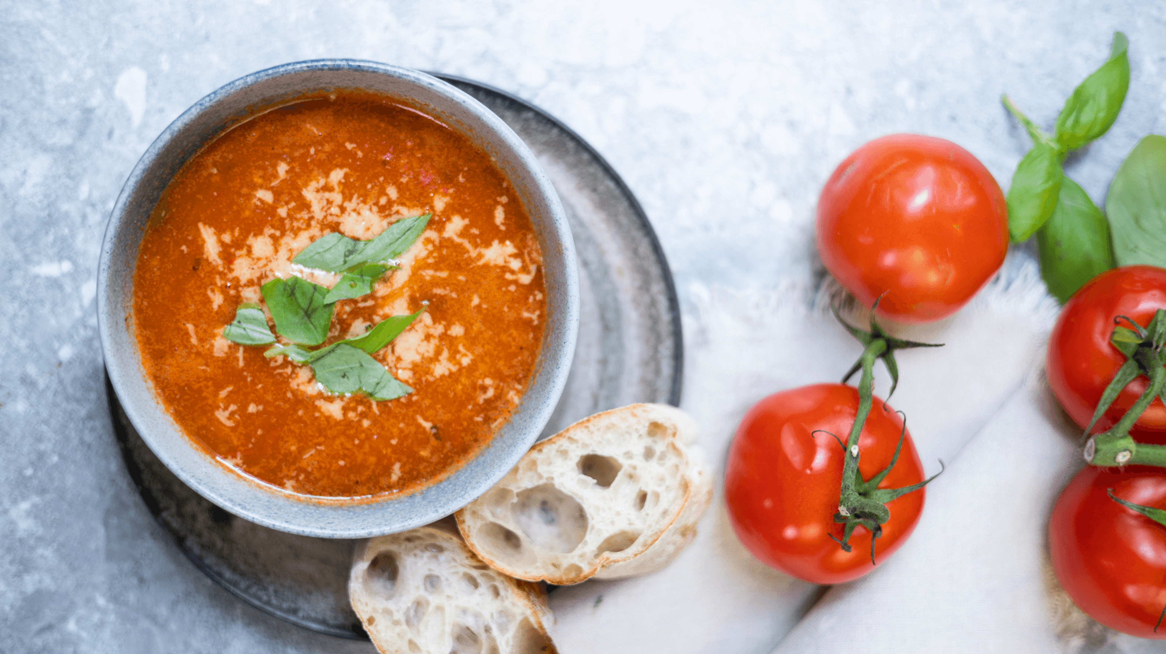 suppeskolen tomatsuppe sett ovenfra med tomater og brød liggende rundt