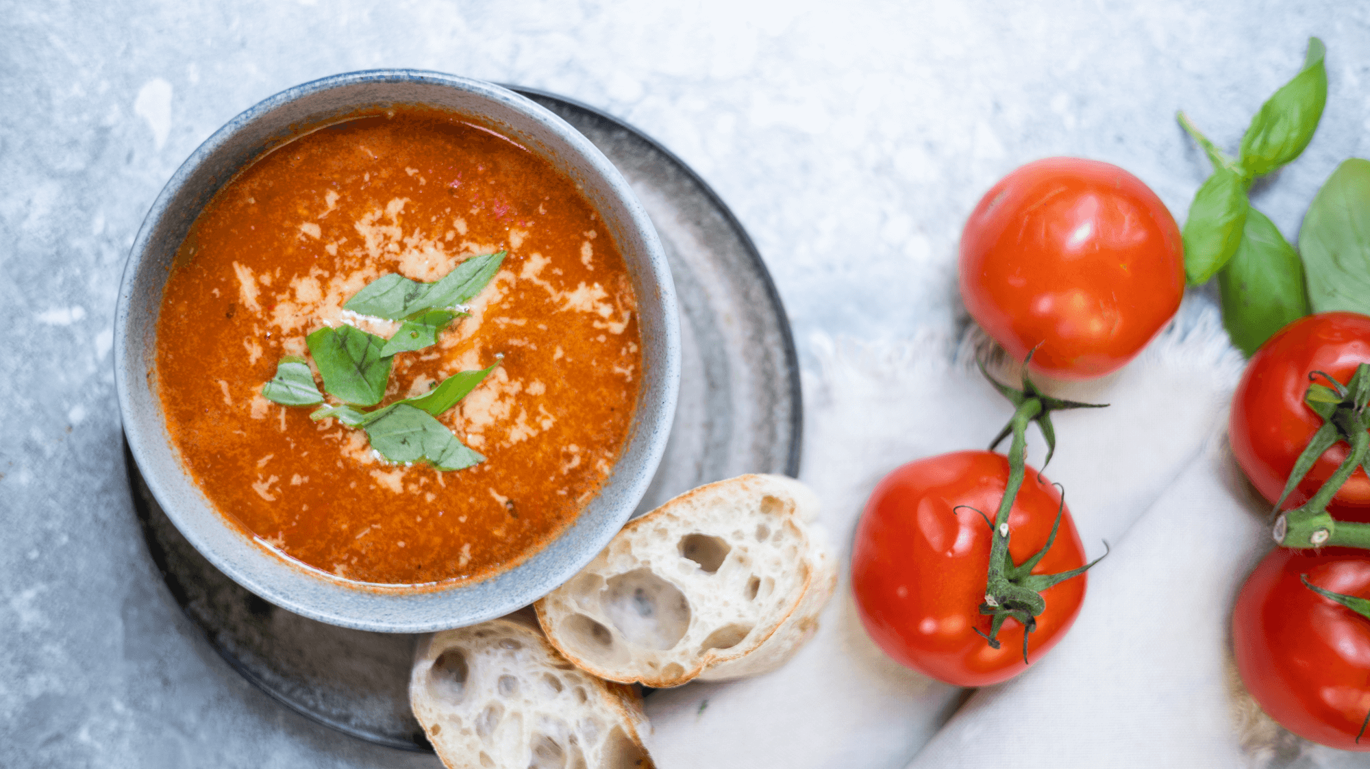suppeskolen tomatsuppe sett ovenfra med tomater og brød liggende rundt