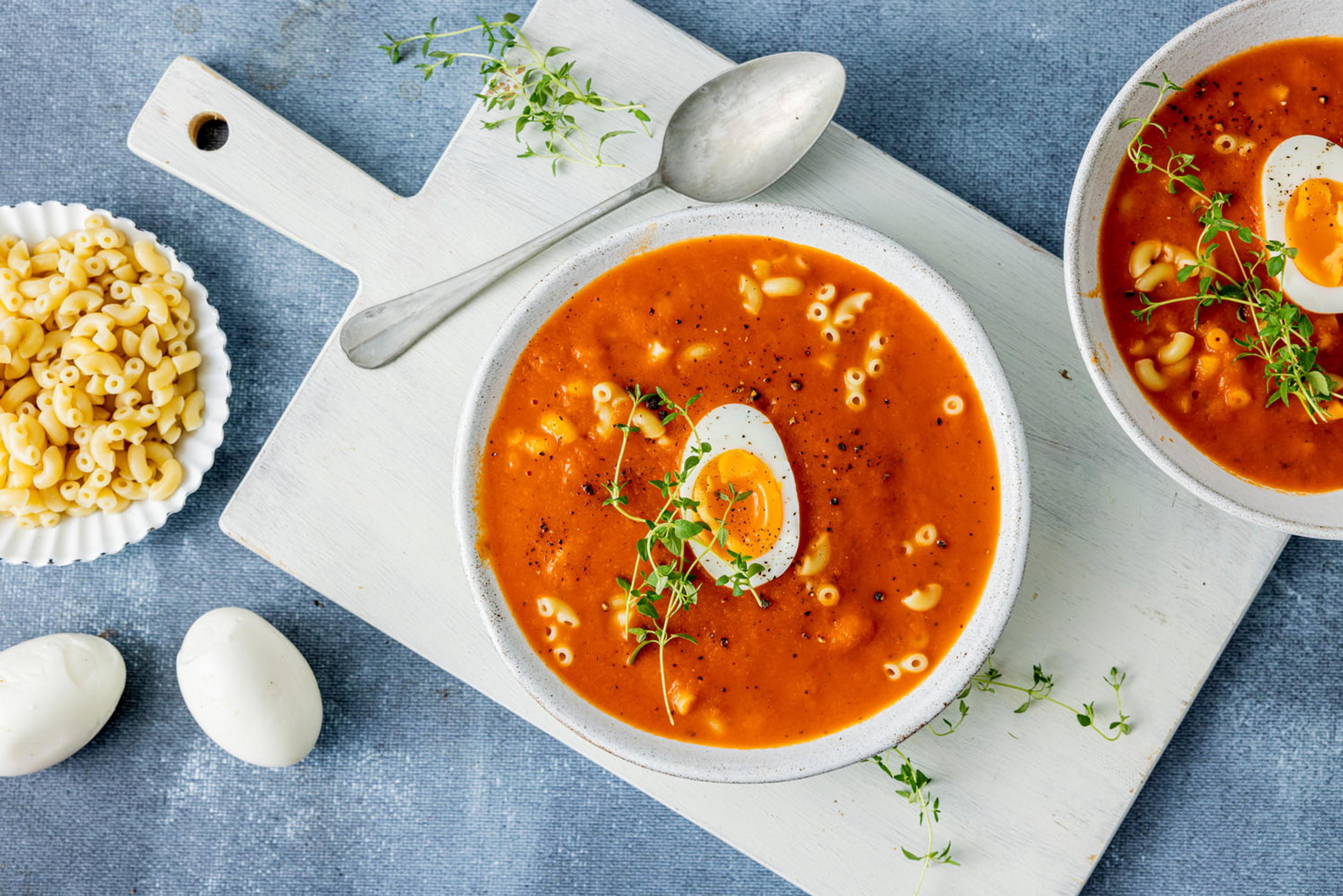 Tomatsuppe med makaroni servert med et delt egg på toppen.