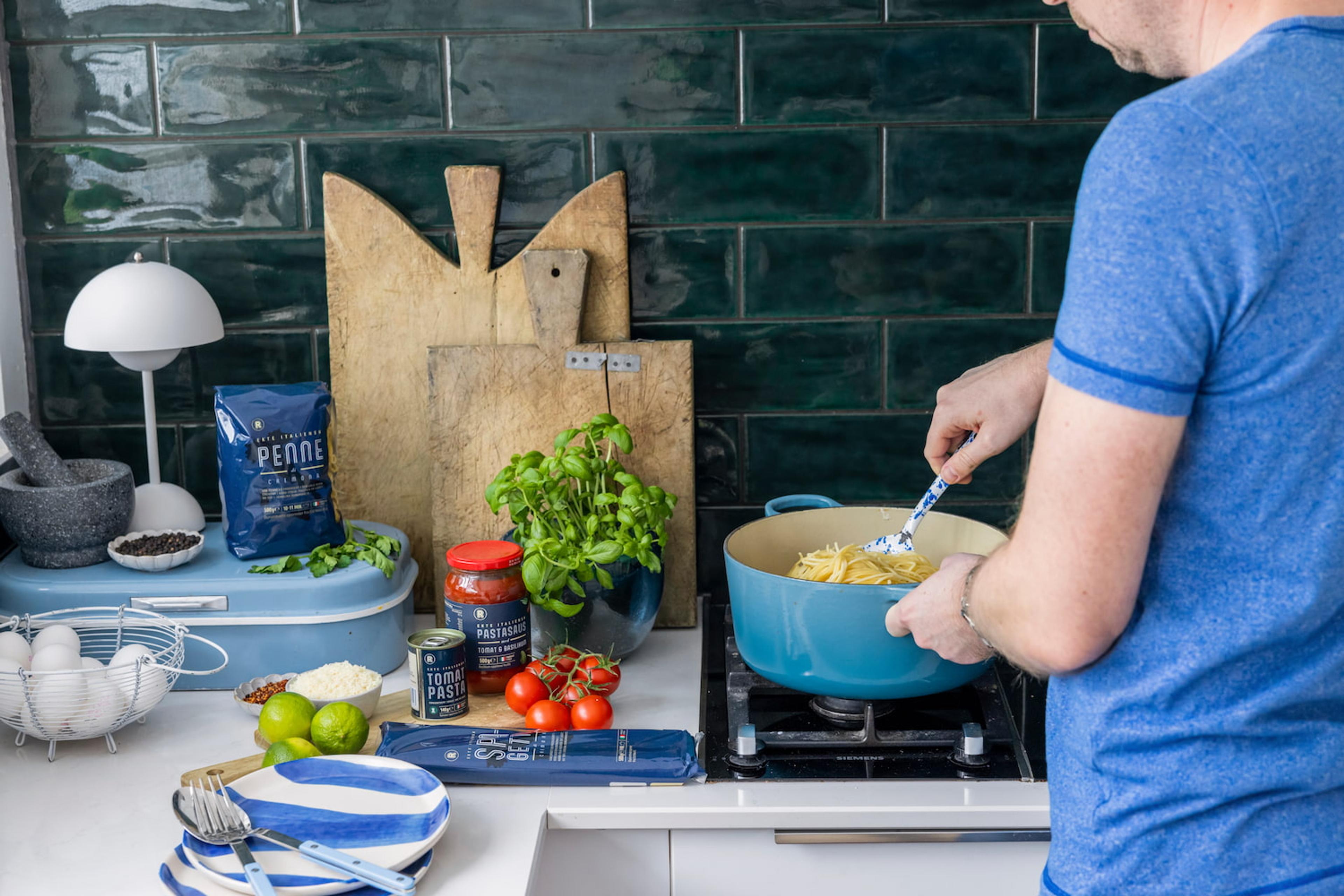 Person lager pastarett på kjøkkenet.