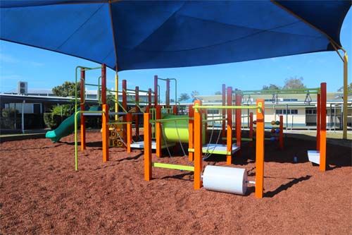 green and orange playground with bark softfall and running wheel