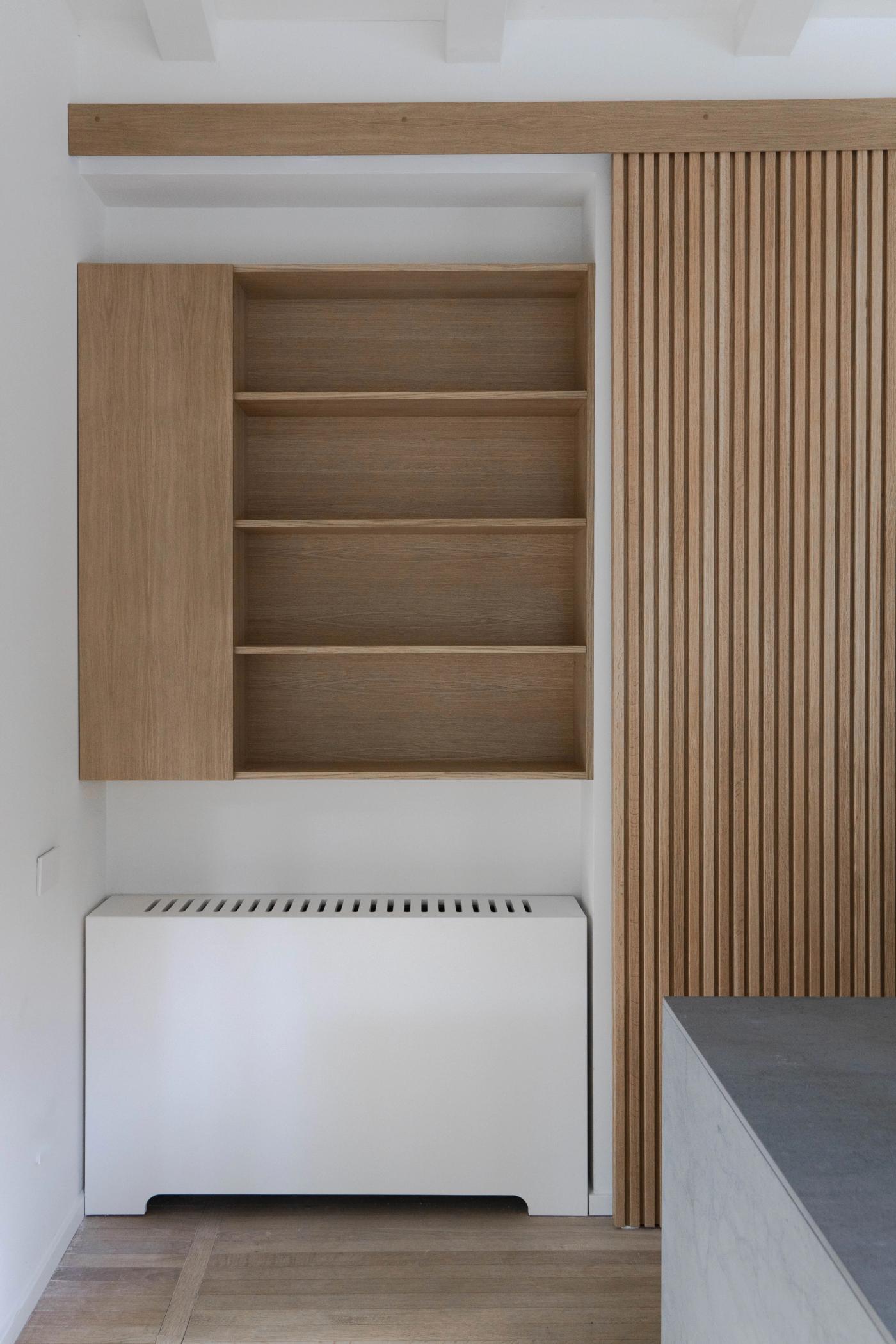 Arredamento su misura in legno con libreria a parete e mobile bianco in stile moderno.