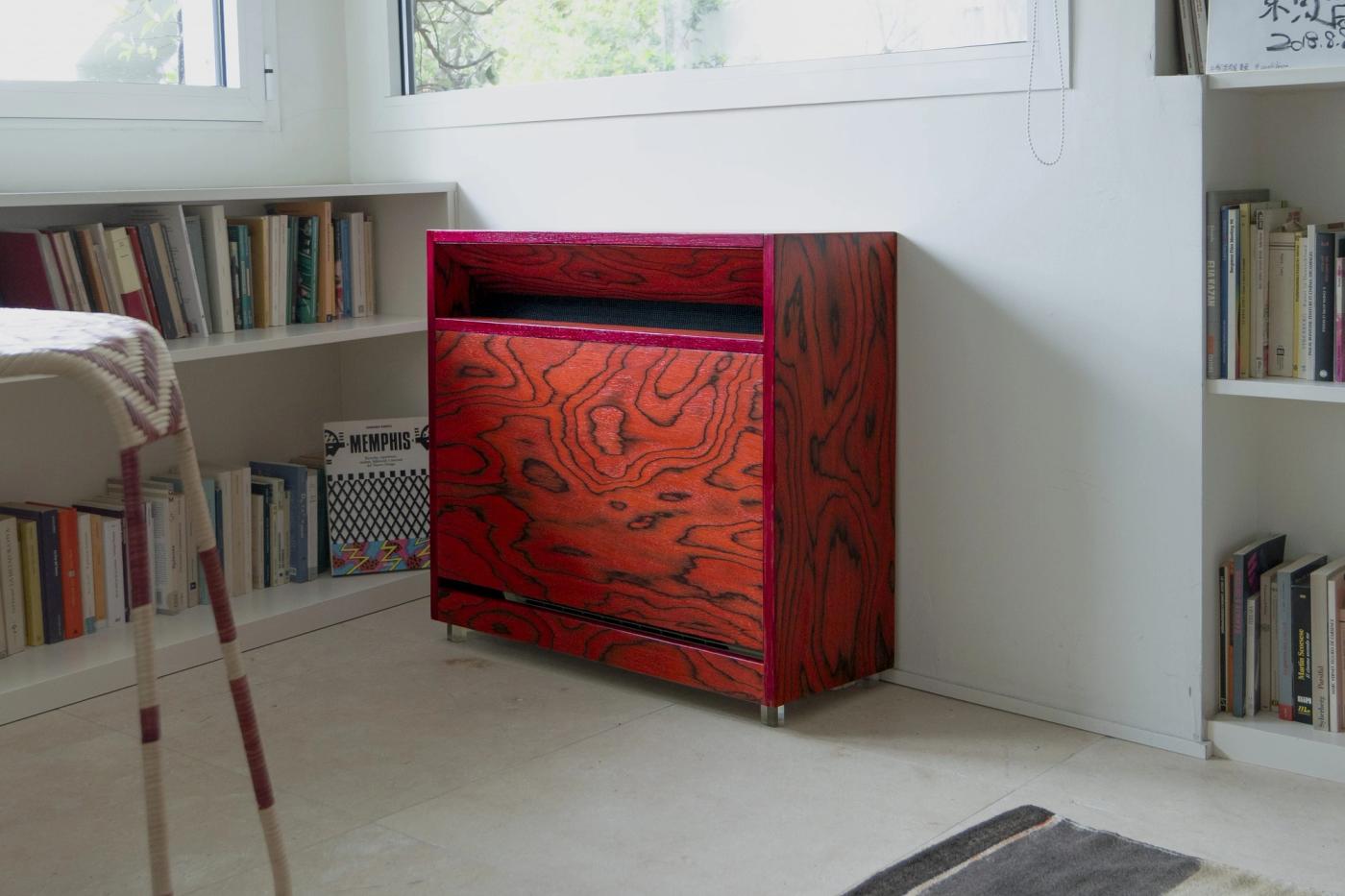 Arredamento su misura in legno rosso con venature naturali, scaffali integrati e serramenti in ambiente luminoso.