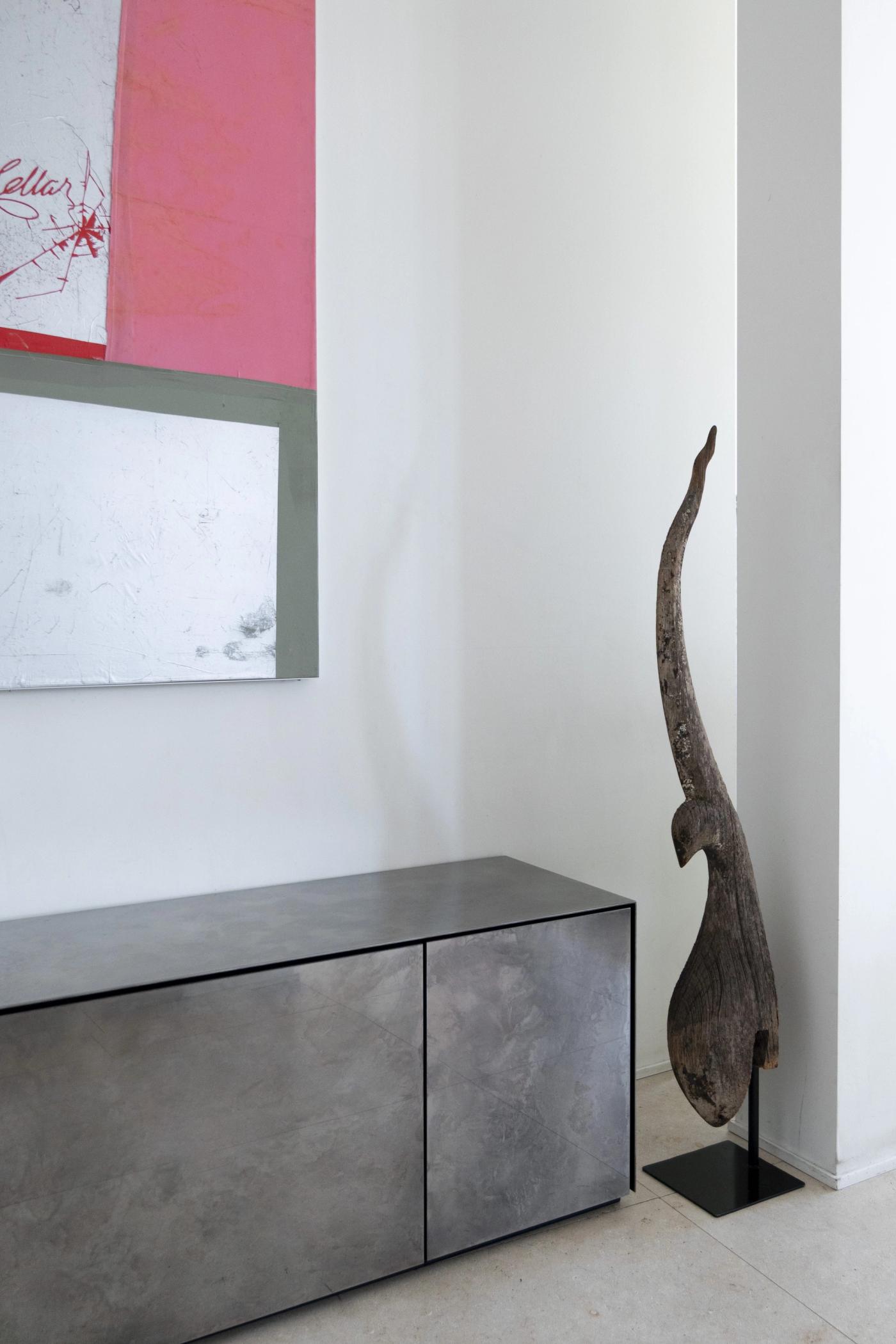 Arredamento su misura moderno con mobile in legno grigio e scultura lignea di design.