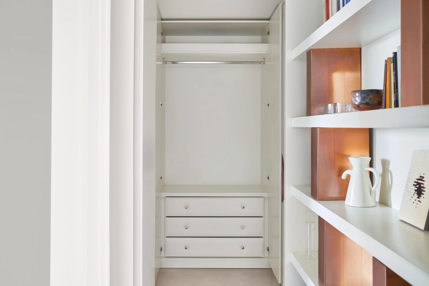 Armadio su misura bianco con cassetti, ripiani e elementi in legno naturale, design minimalista.