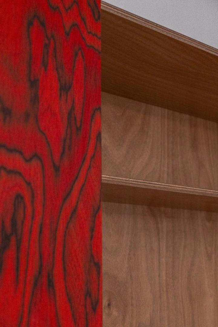 Libreria in legno con ripiani in noce e tenda rossa, falegnameria Loreti e Sibilla.