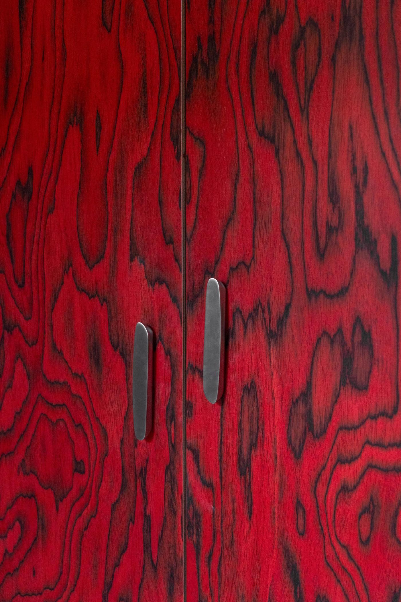 Porta in legno rosso con venature naturali e maniglie metalliche moderne.