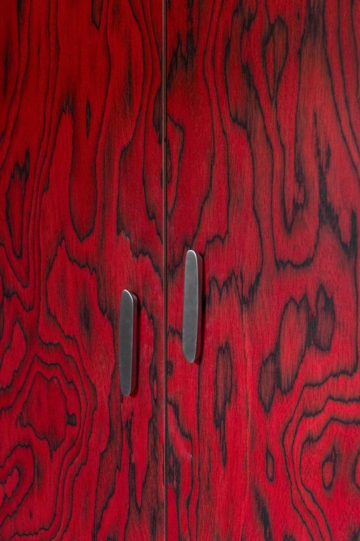 Porta in legno rosso con venature naturali e maniglie metalliche moderne.