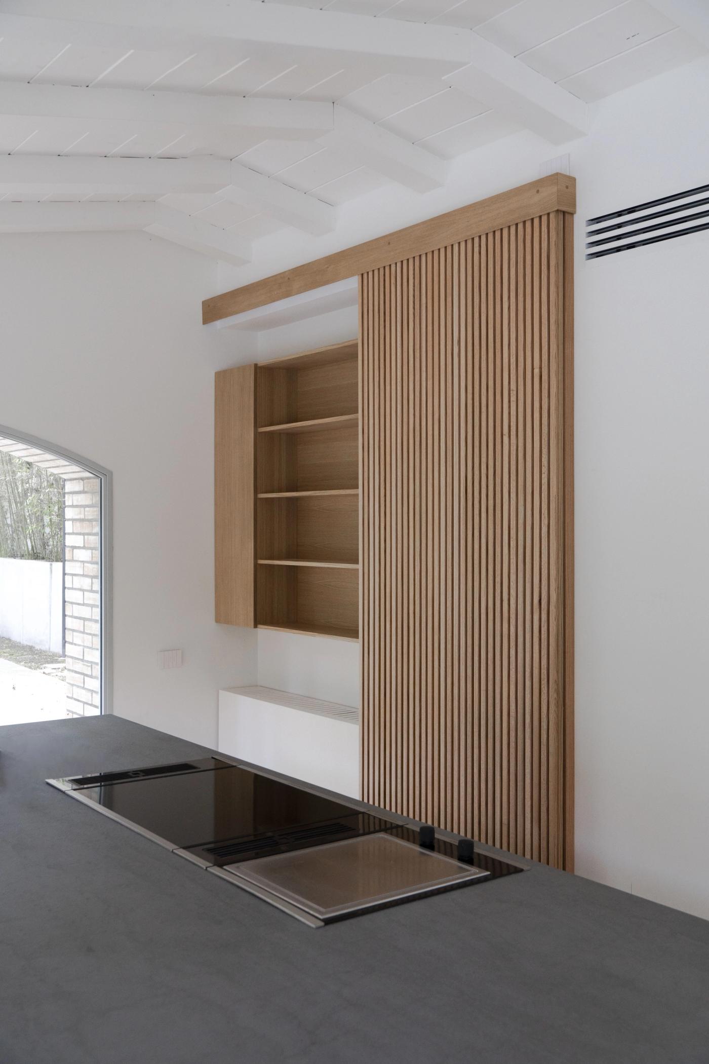 Arredamento su misura in legno con libreria a parete e sportelli a doghe verticali, design moderno.