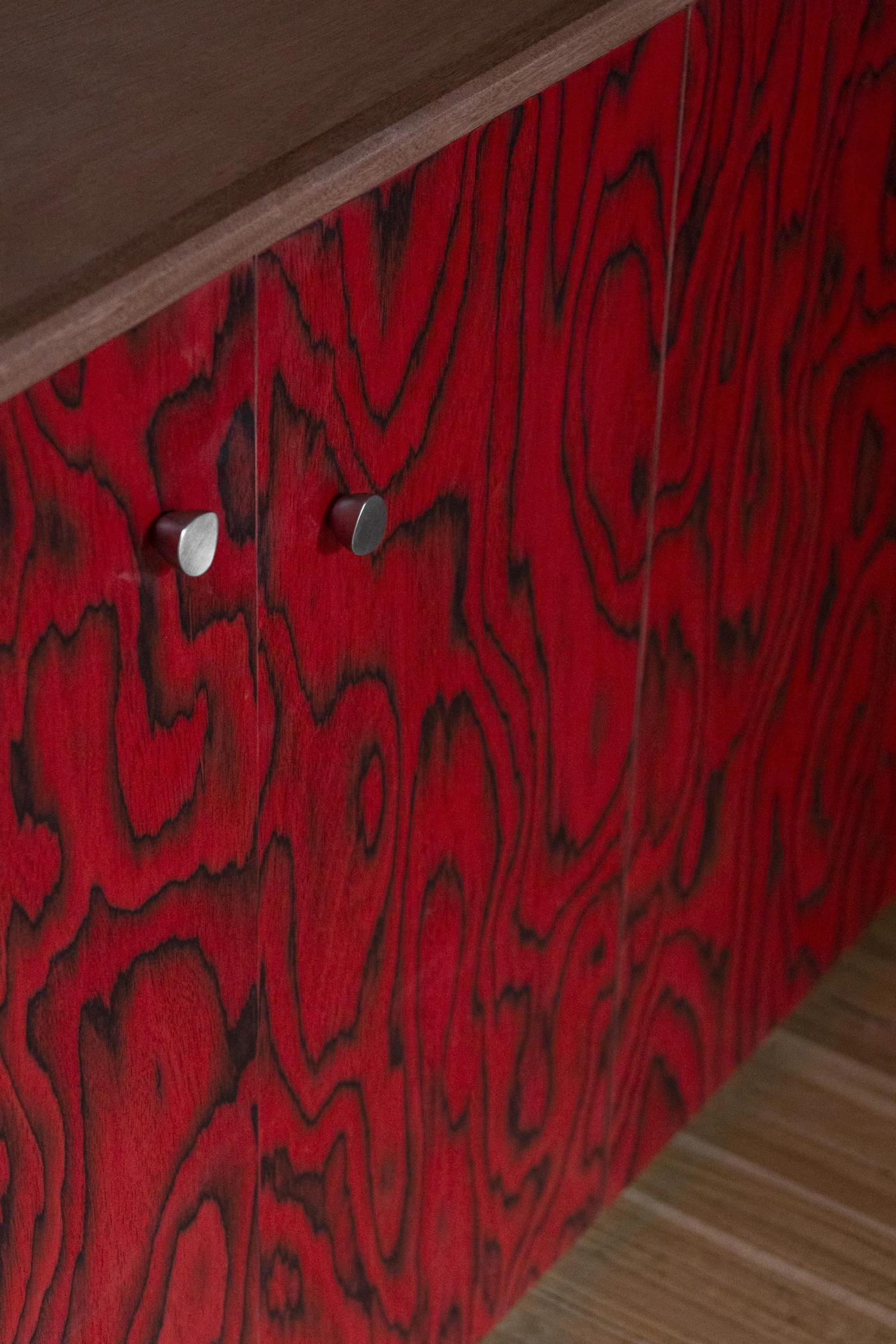 Mobile credenza in legno rosso tinto con maniglie metalliche e venature naturali evidenziate.