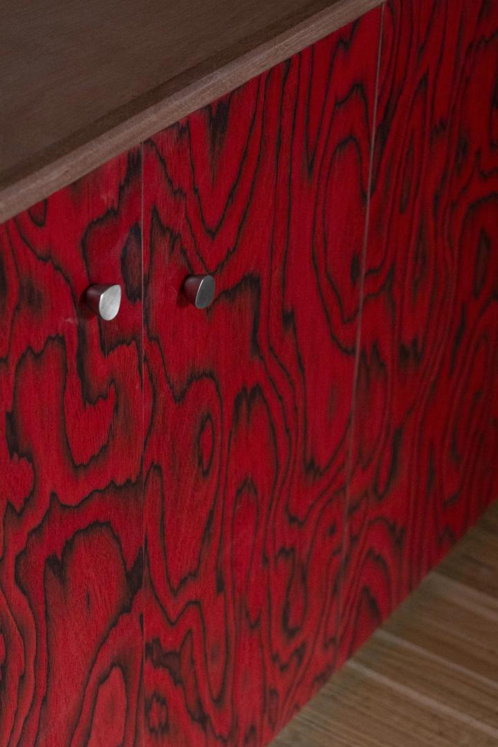 Mobile credenza in legno rosso tinto con maniglie metalliche e venature naturali evidenziate.