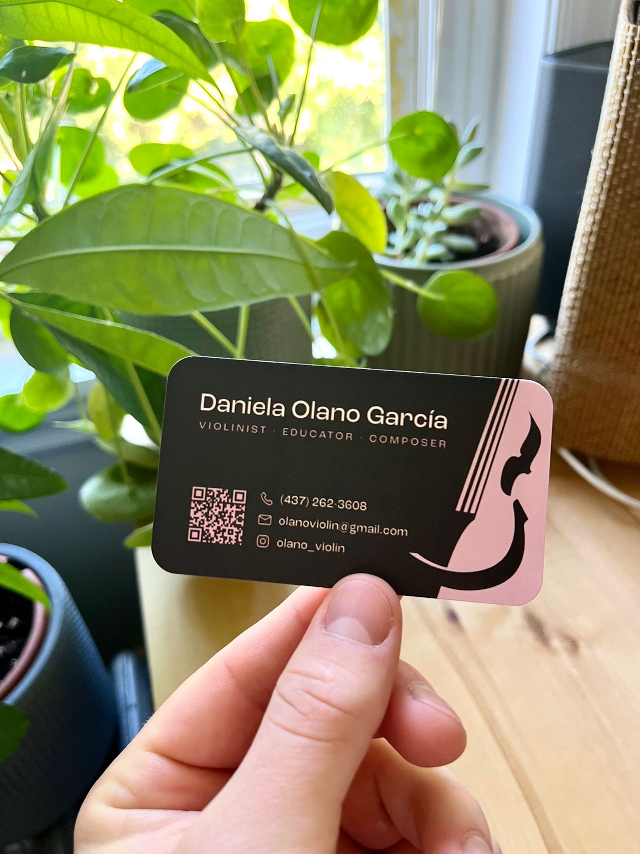The front of Daniela's business card. Dark with name, violin graphic, QR code, and contact info.