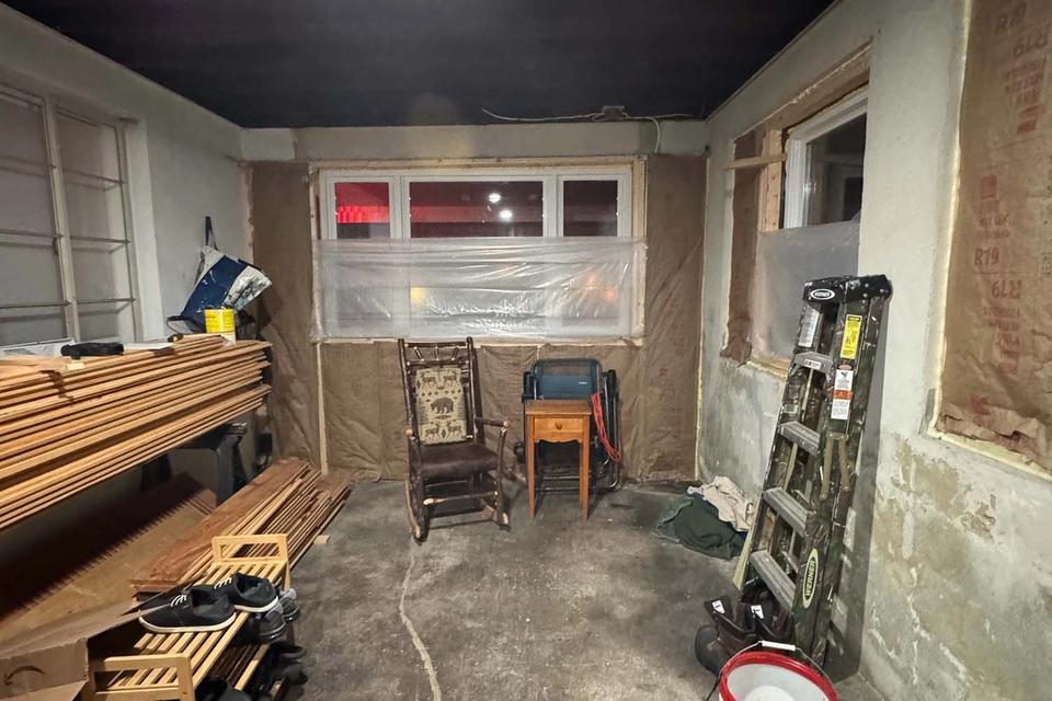 Unfinished garage interior with exposed walls, stacked lumber, a ladder and concrete floor