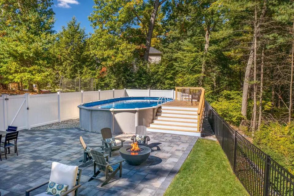 Completed pool deck and broad stairs behind a patio seating area with a fire pit