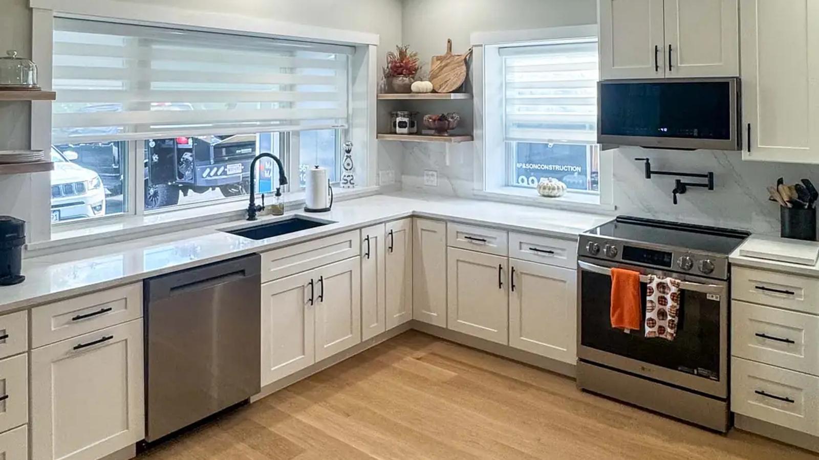 Completed white kitchen with stainless steel appliances, wood flooring and a vaulted plank ceiling