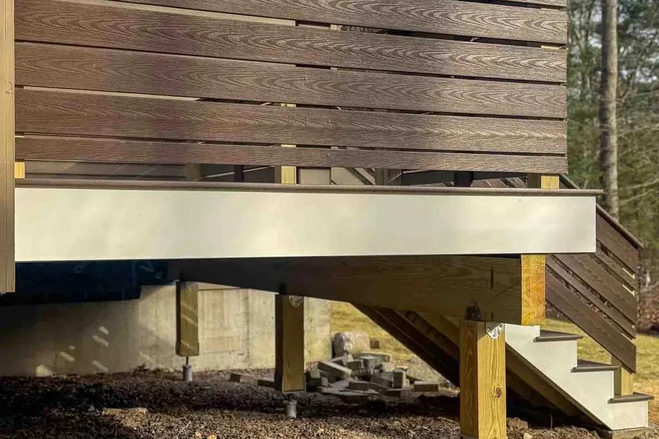 Horizontal deck railing above white fascia and exposed support posts