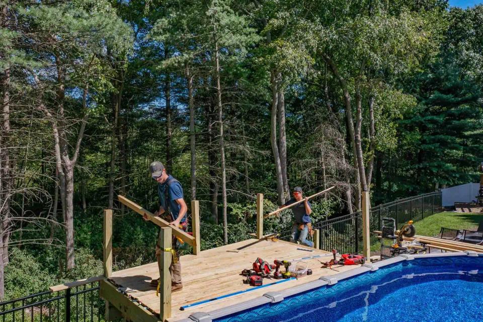 Wood deck beside the pool with upright railing posts and carpenters fitting boards
