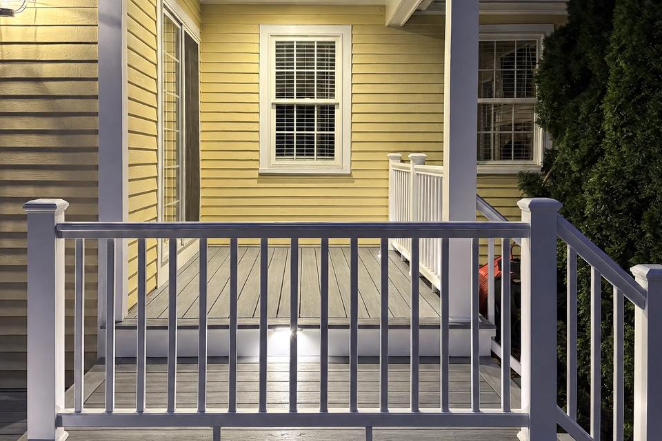 Front view of the covered porch, white railing and illuminated steps at night