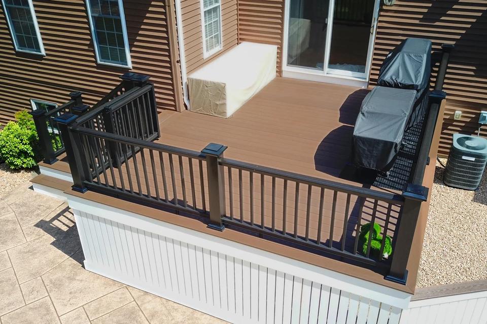 Brown composite deck with black railings, covered grills and white vertical skirting
