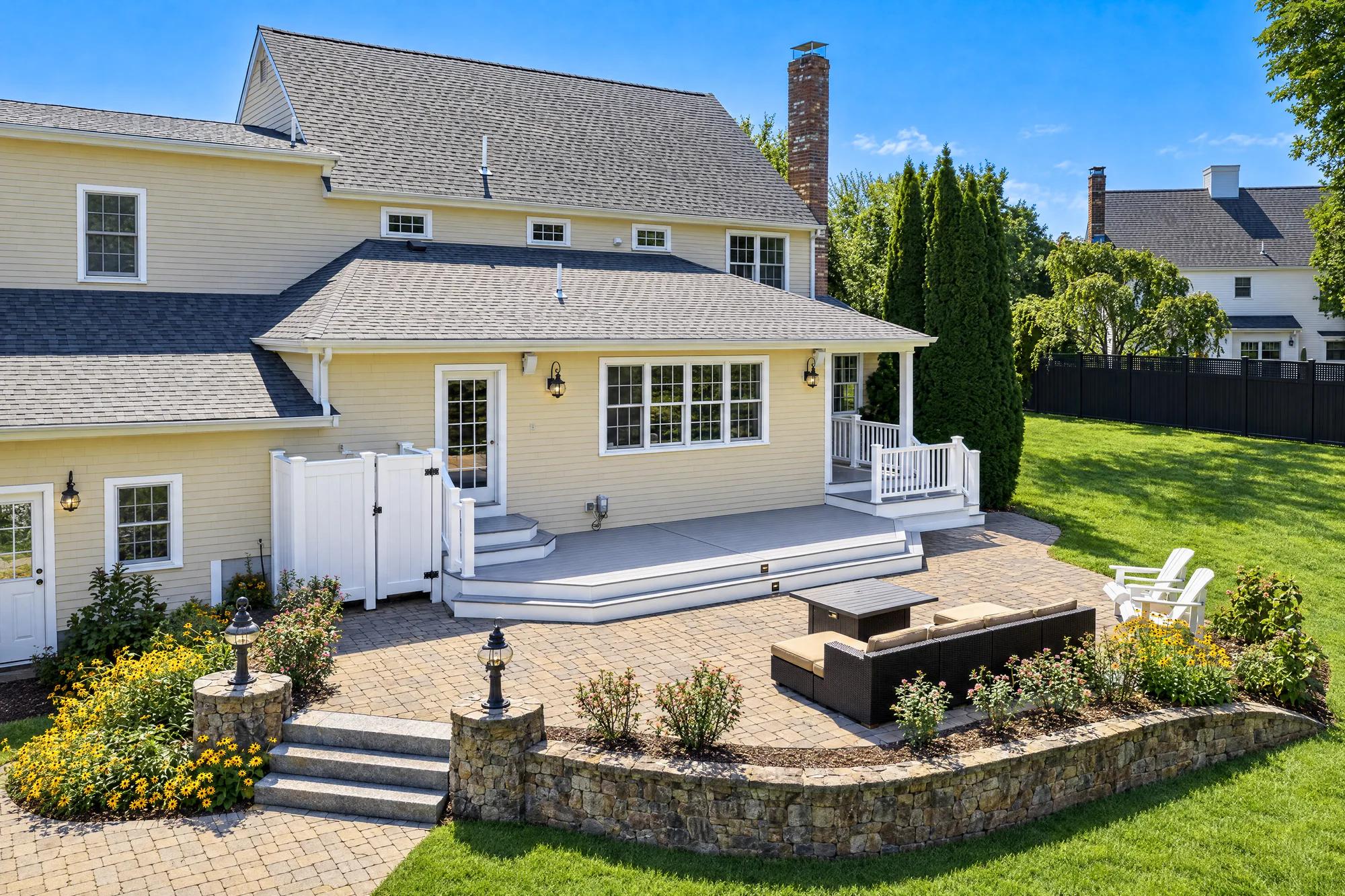 Completed grey deck with white railings overlooking the existing backyard patio