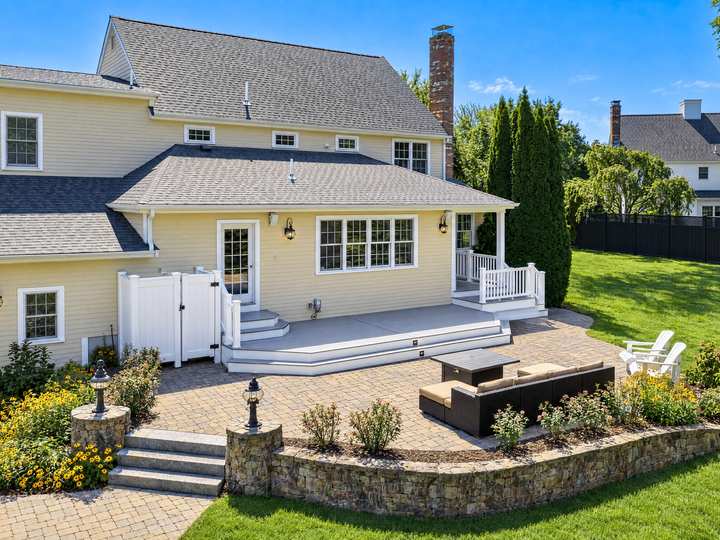Completed grey deck with white railings beside a yellow house in North Easton