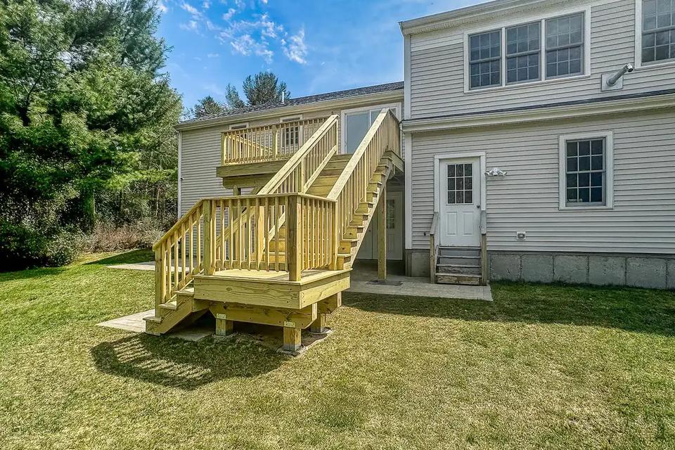 Completed elevated wood deck and two-part staircase viewed from the backyard