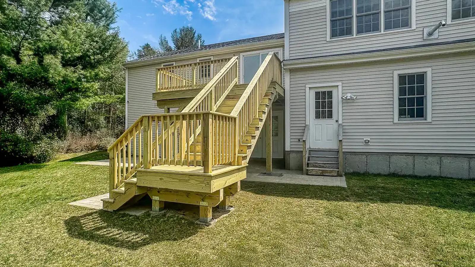 Completed elevated wood deck and two-part staircase viewed from the backyard