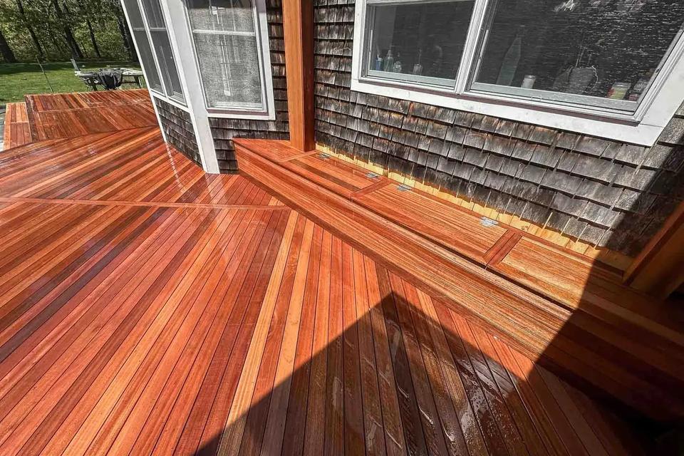 Mahogany decking with contrasting border boards following the wall beneath white-trimmed windows