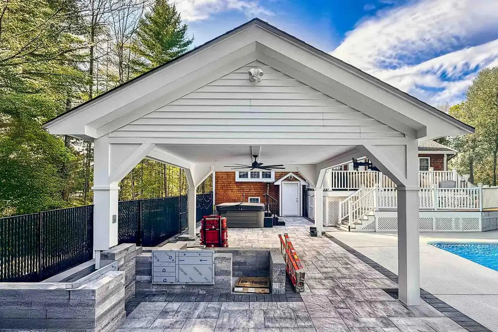 White gabled pool pavilion with masonry outdoor kitchen walls under construction