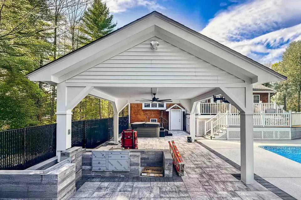 White gabled pool pavilion with masonry outdoor kitchen walls under construction