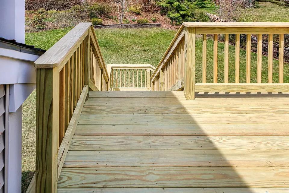 Wood deck boards and vertical baluster railings surrounding the stair opening