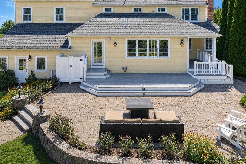 Front view of the completed deck, white railings and existing patio seating