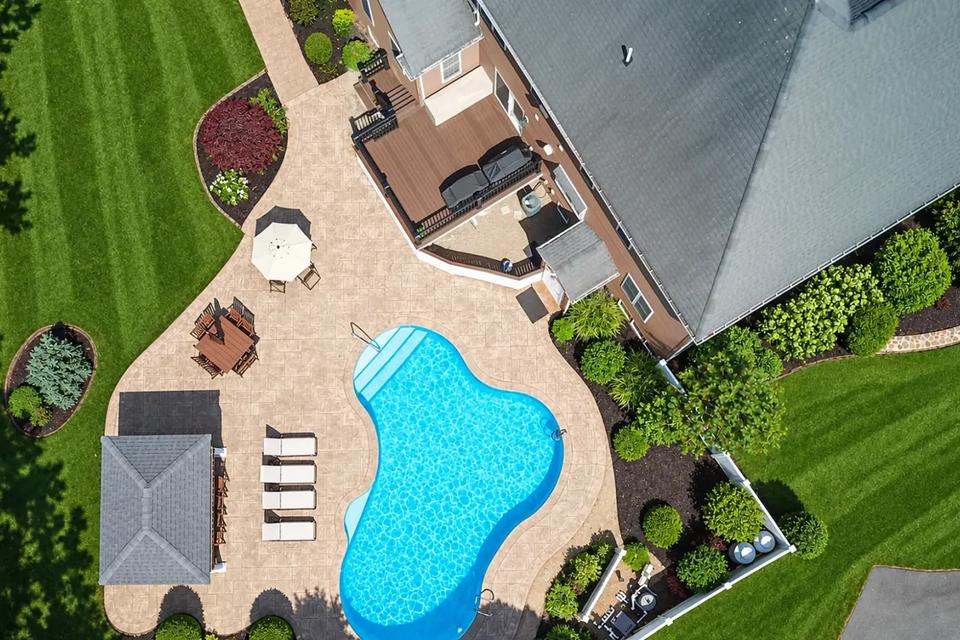 Top-down view of the swimming pool, surrounding patio and composite deck beside the house