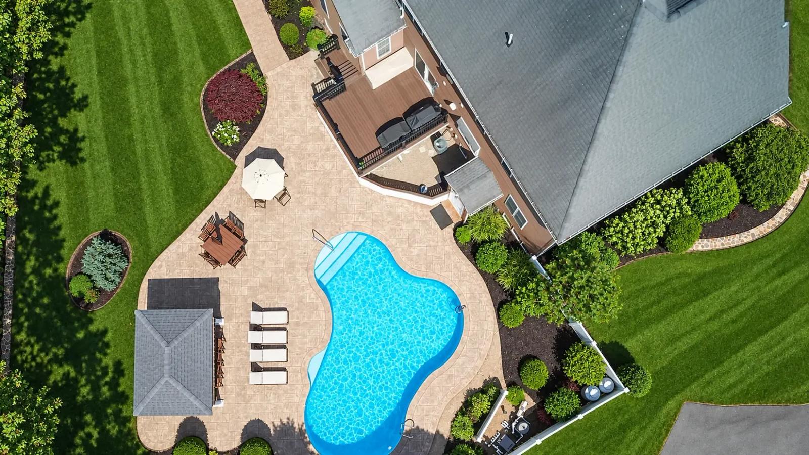 Top-down view of the swimming pool, surrounding patio and composite deck beside the house