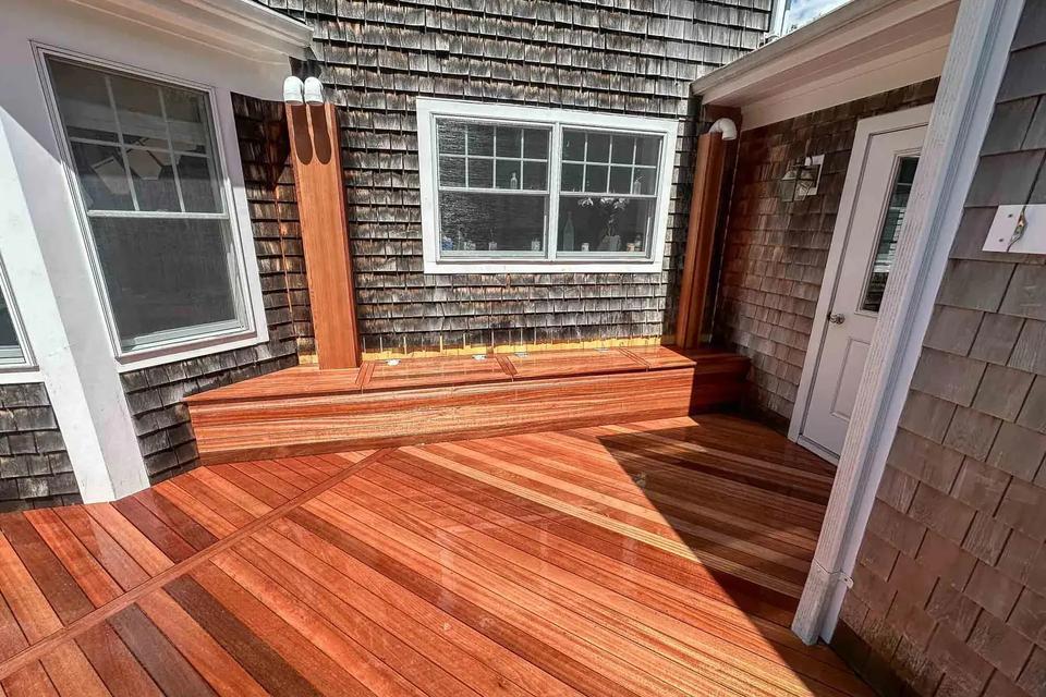 Mahogany deck and a small raised step at a side door between shingled walls