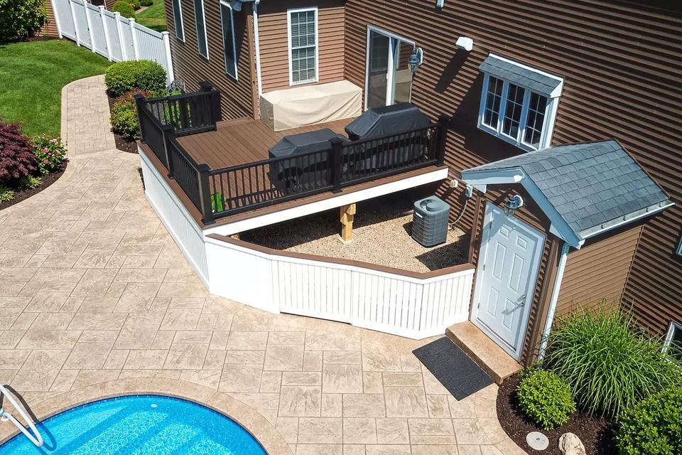 Aerial view of the deck, covered grills and white enclosure beside the swimming pool